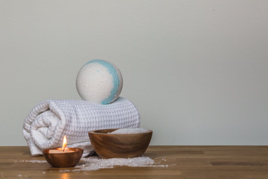 Peaceful spa setting with bath bomb, salt, candle, and towel, perfect for relaxation